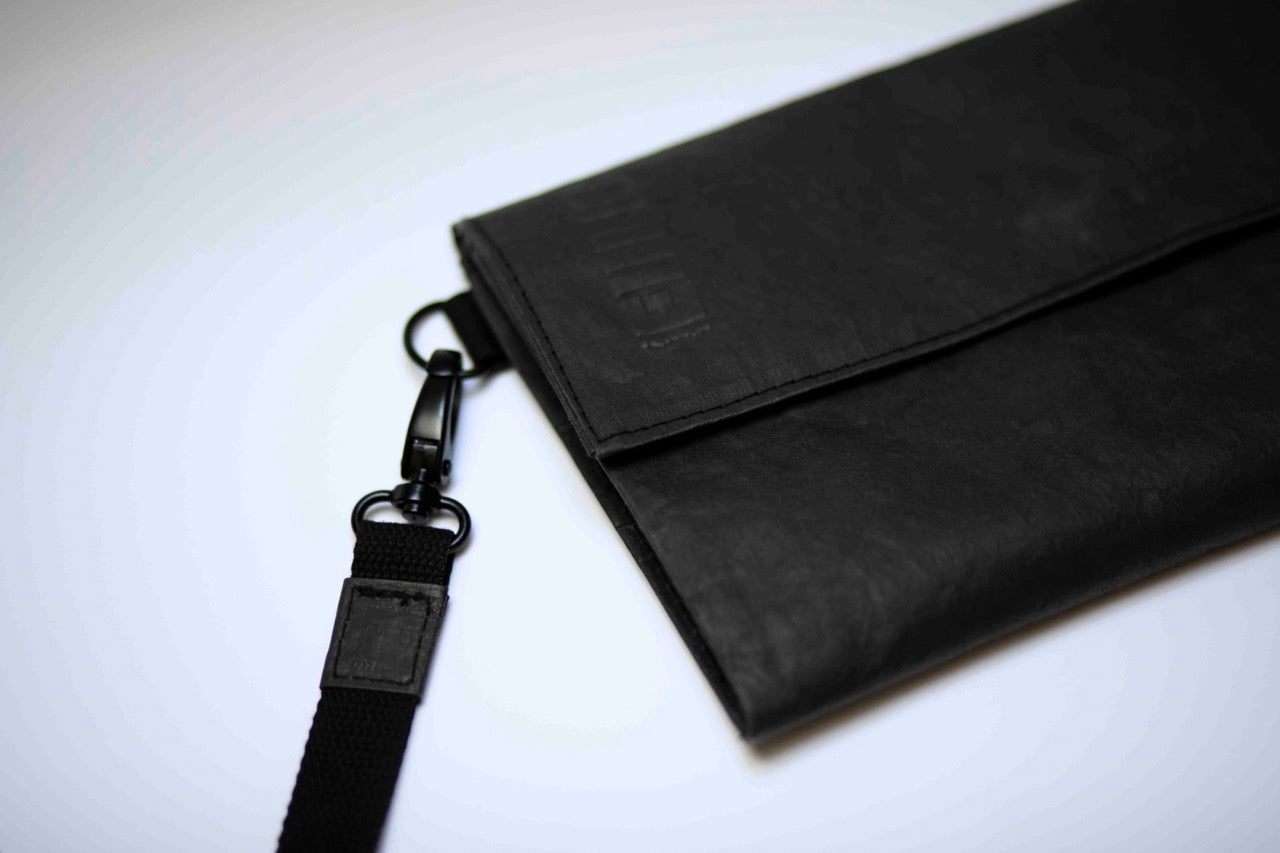 Fiilii design melna clutch soma uz balta fona