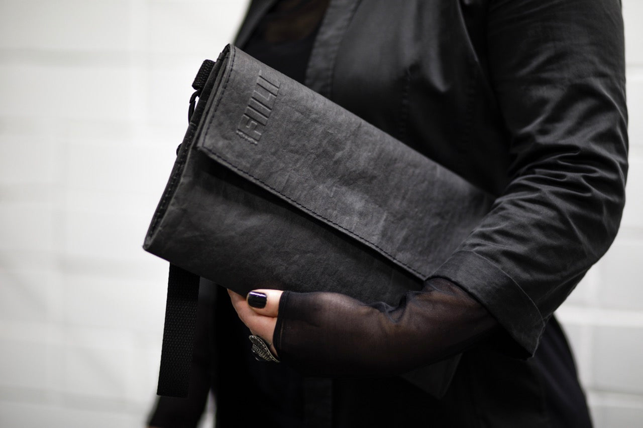 Fiilii design melna clutch somiņa sievietes rokās horizontāli